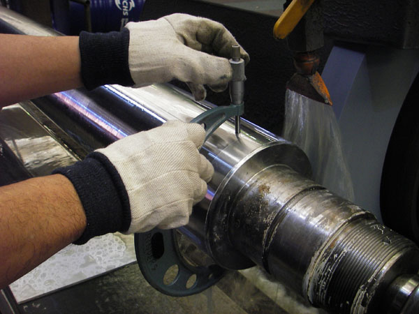 Machinist using micrometer on hydraulic cylinder